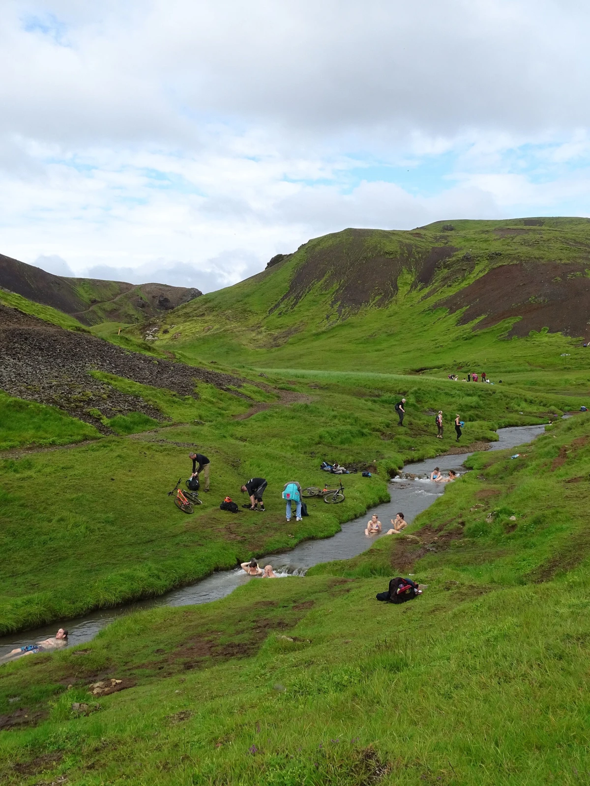 People bathing in the warm mountain river in Iceland's Reykjadalur valley.