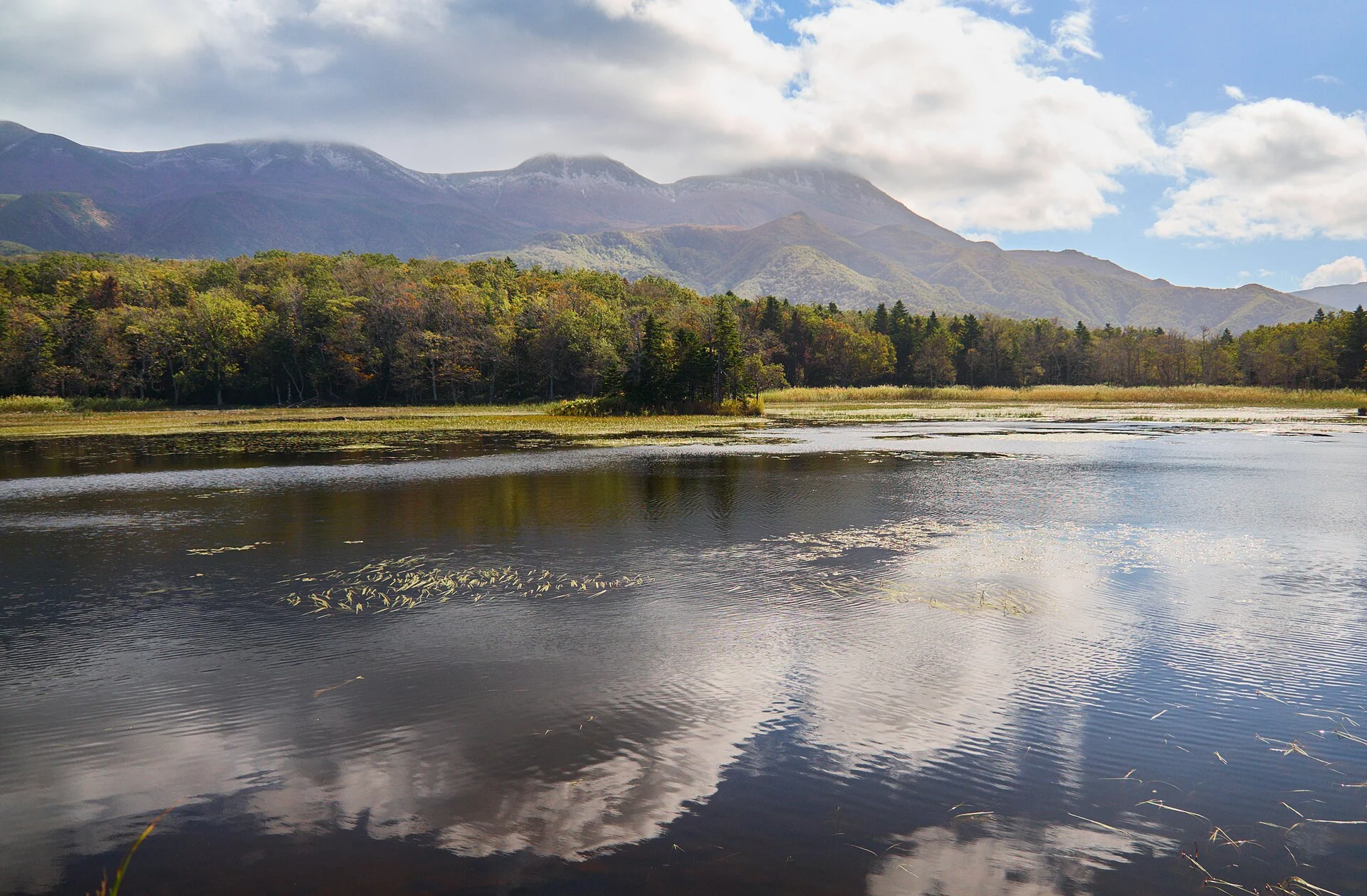 One of Shiretoko's Five Lakes framed by mountains and autumn vegetation.