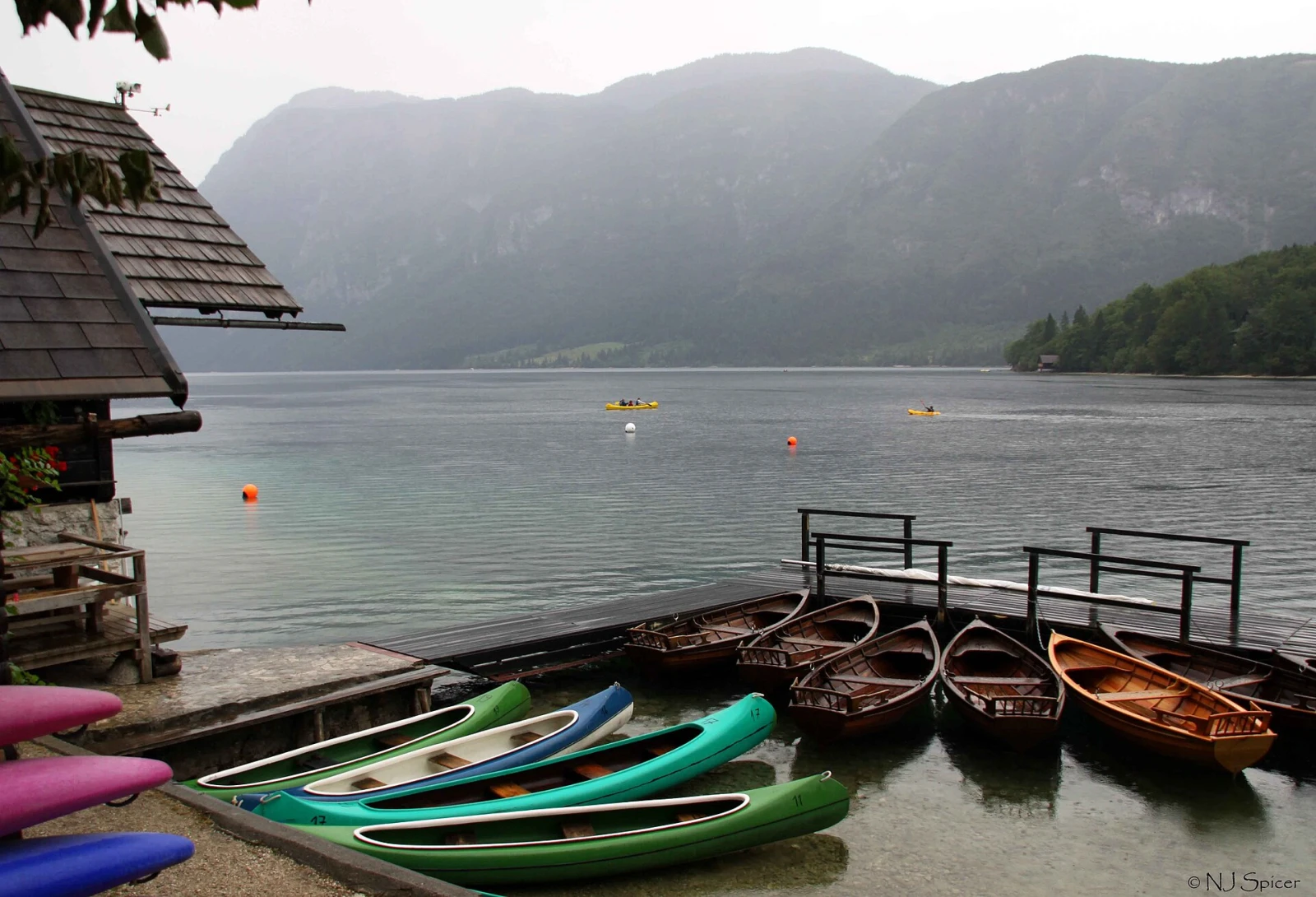 Kayaks lined up beside Lake Bohinj and the Julian Alps.
