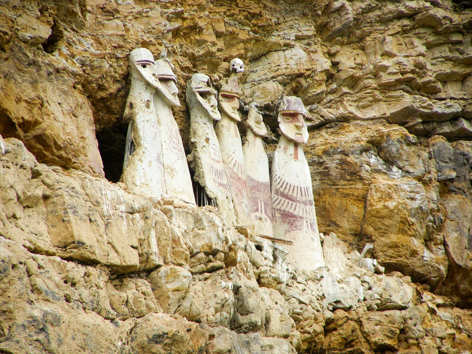 Tall painted Chachapoya sarcophagi standing in a cliff recess at Karajía.