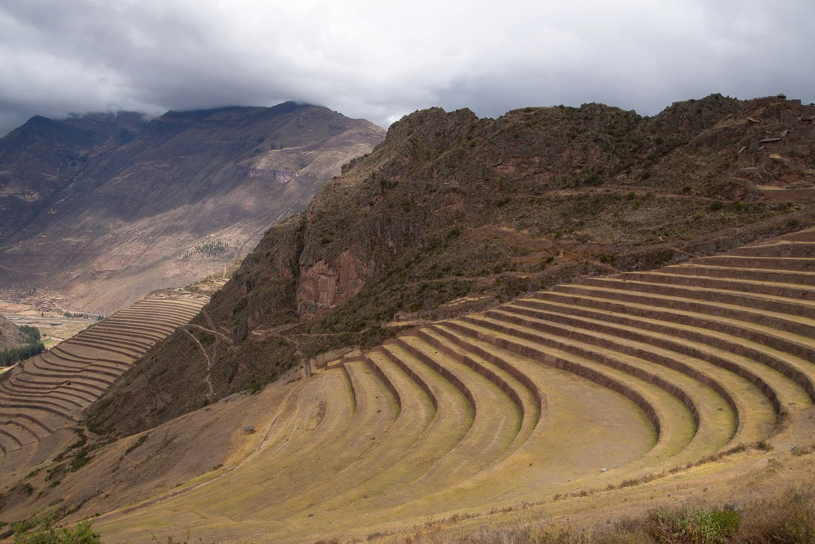 Pisac's sweeping Inca terraces curving beneath cloud-covered Andean peaks.