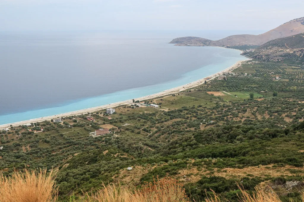 Borsh's long pale shore curving beneath olive-covered hills on the Albanian Riviera.