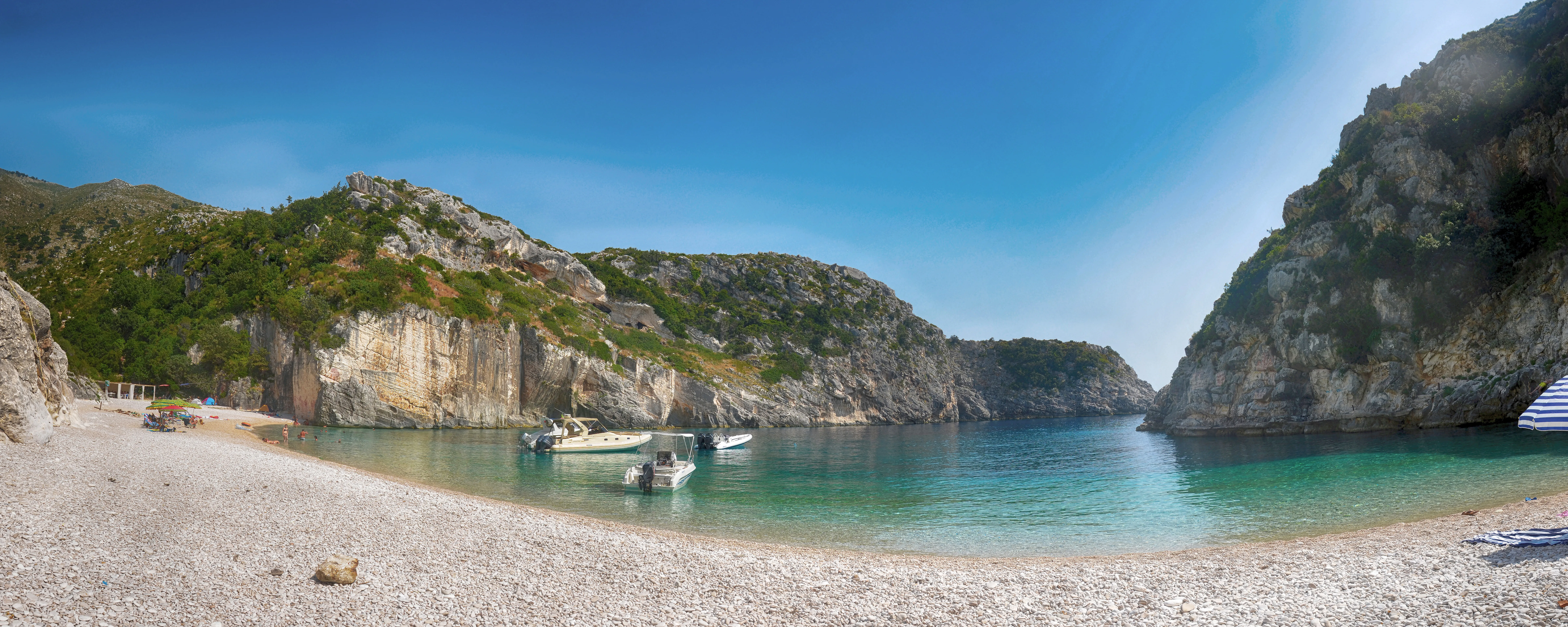 Boats floating in the clear water beneath the limestone walls of Grama Bay.