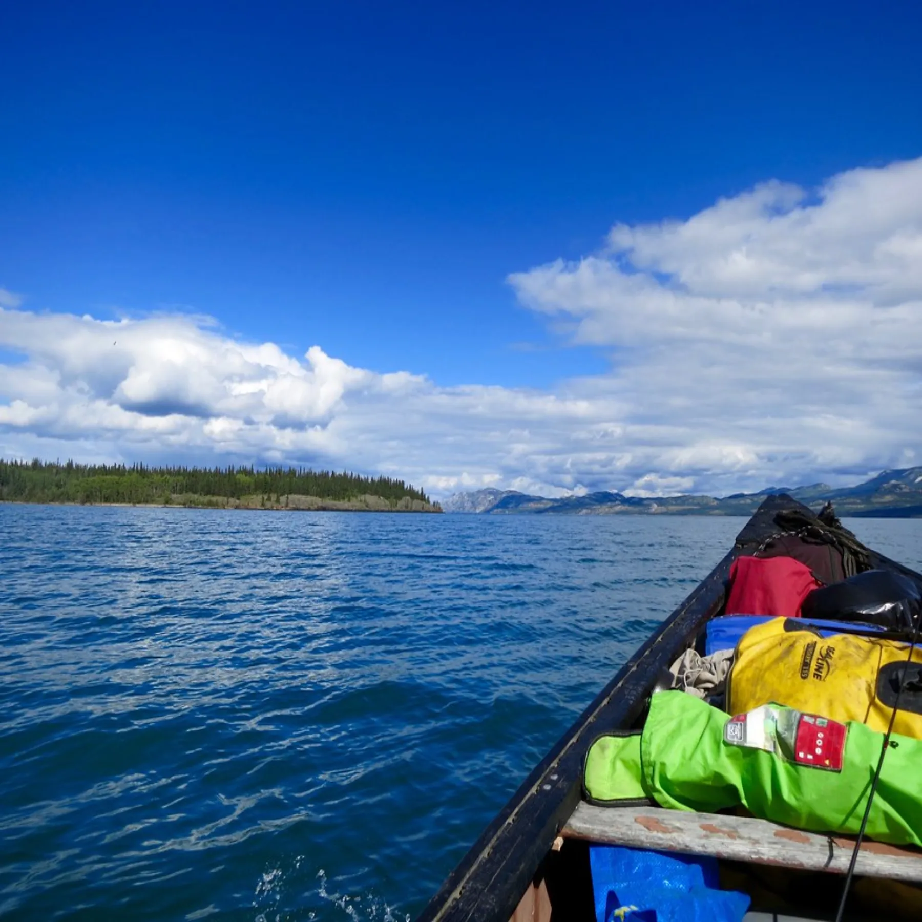 A canoe travelling along the Yukon River with expedition gear aboard.