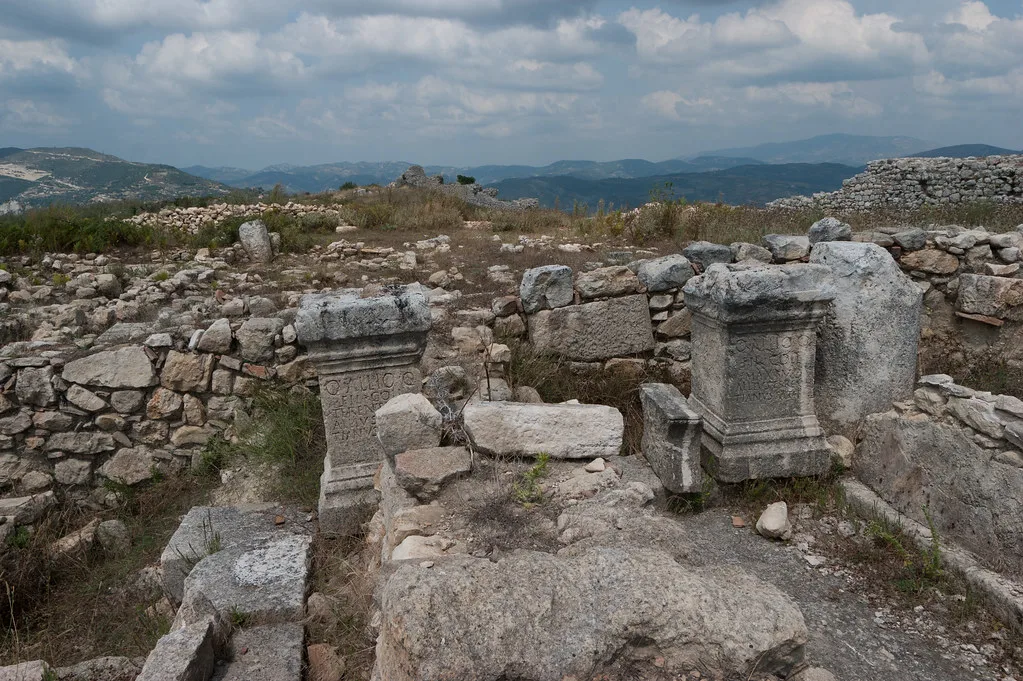 Ancient carved stone fragments and low walls at the hilltop ruins of Byllis.