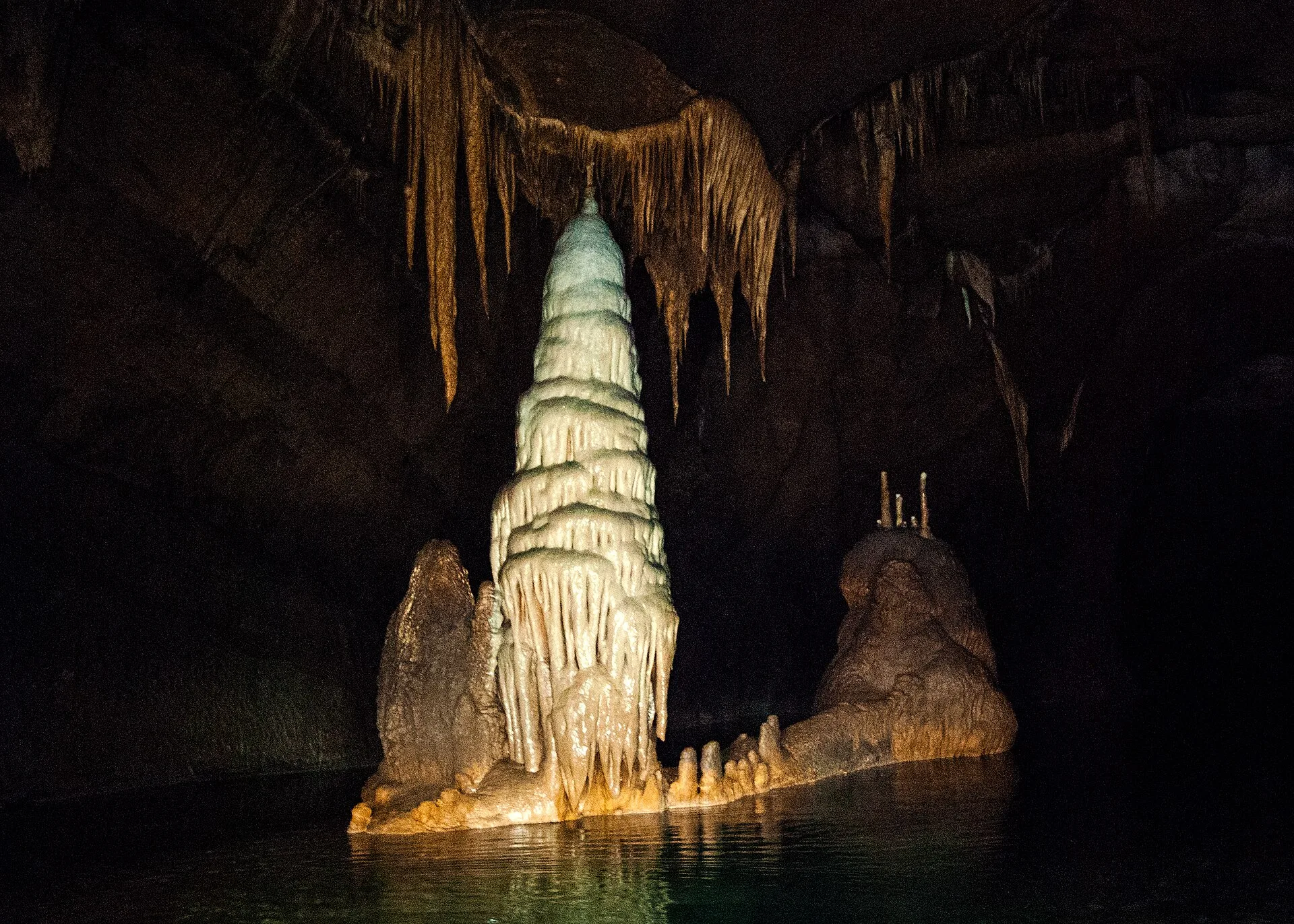 The Pirate's Boat stalagmite formation rising from an underground lake in Križna Cave.