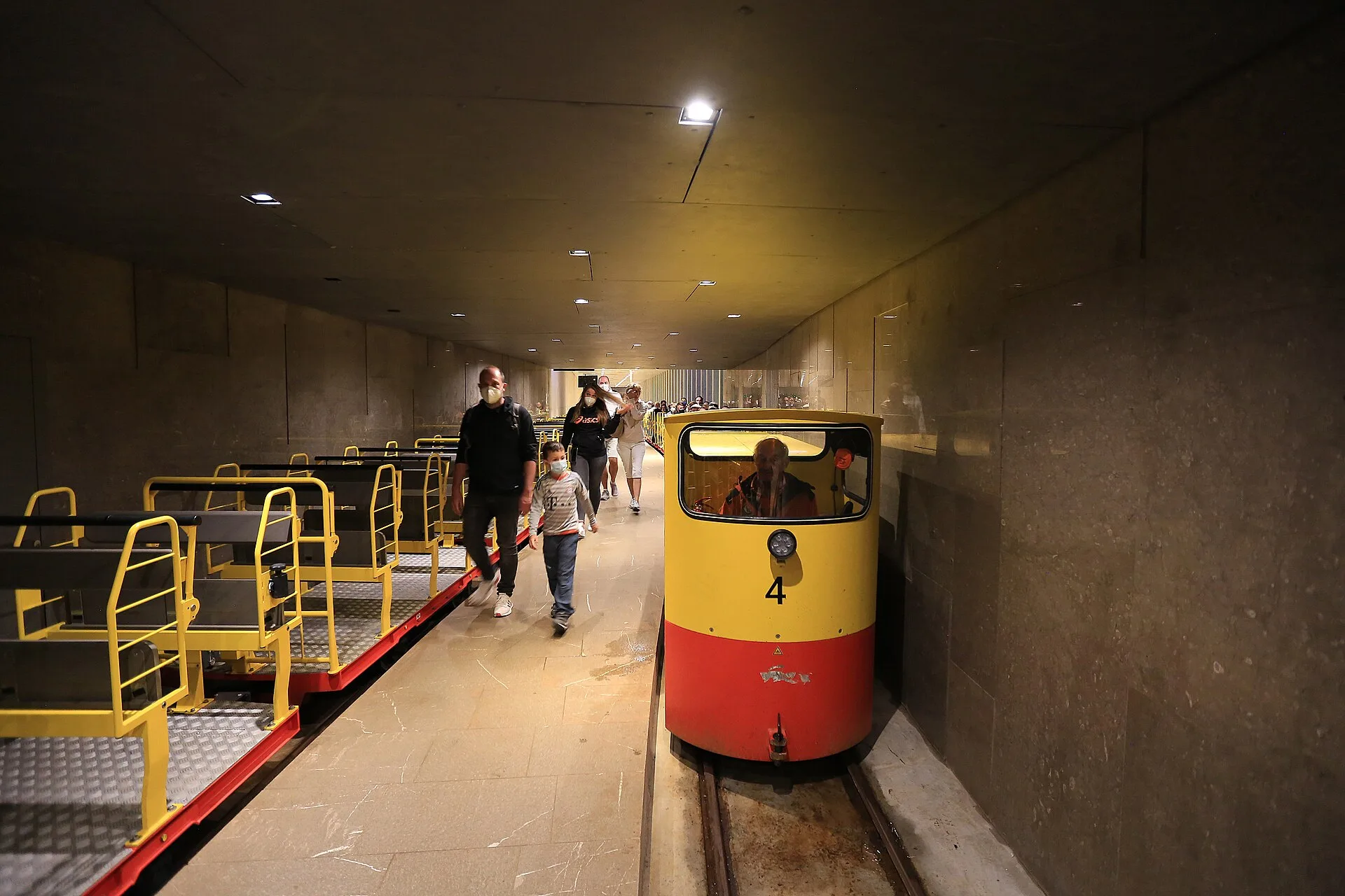 A yellow visitor train waiting on the underground railway platform in Postojna Cave.