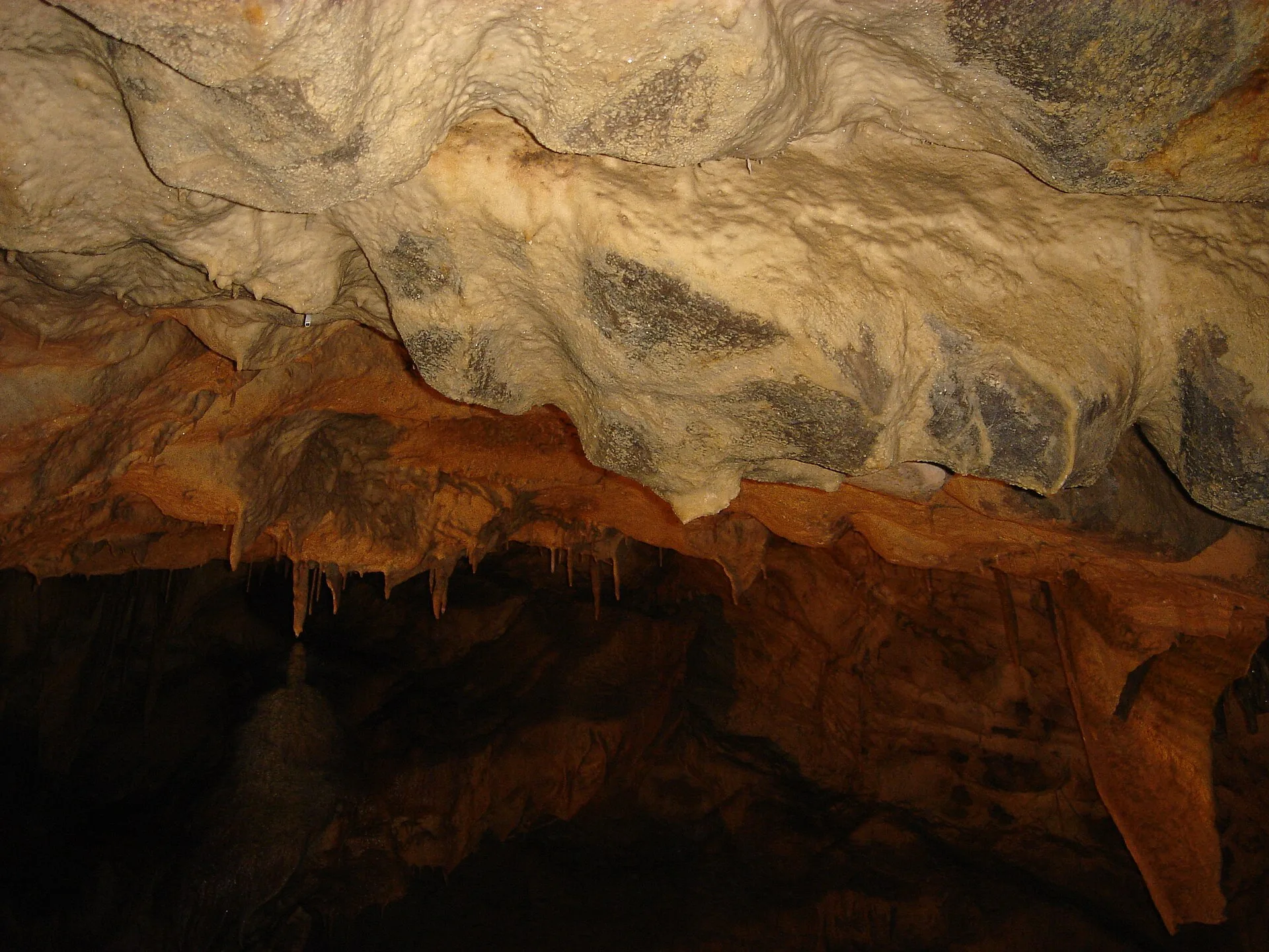Limestone formations and a dark passage inside Škocjan Caves.
