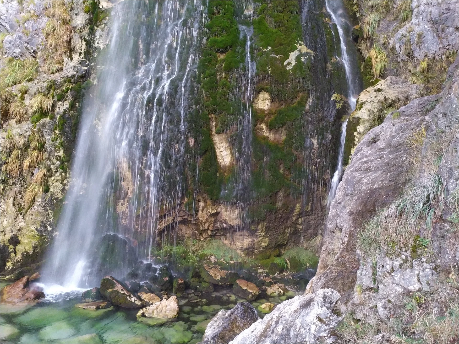 Grunas Waterfall falling down a mossy rock face in Theth.