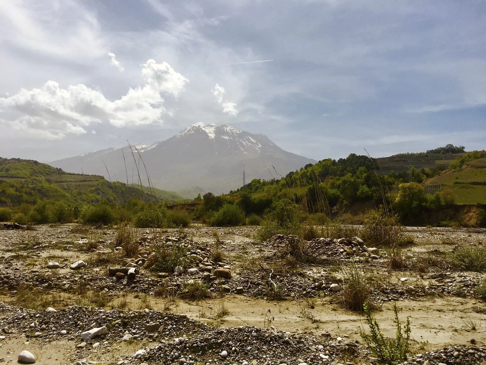 Mount Tomorr rising above fields and a river valley in central Albania.