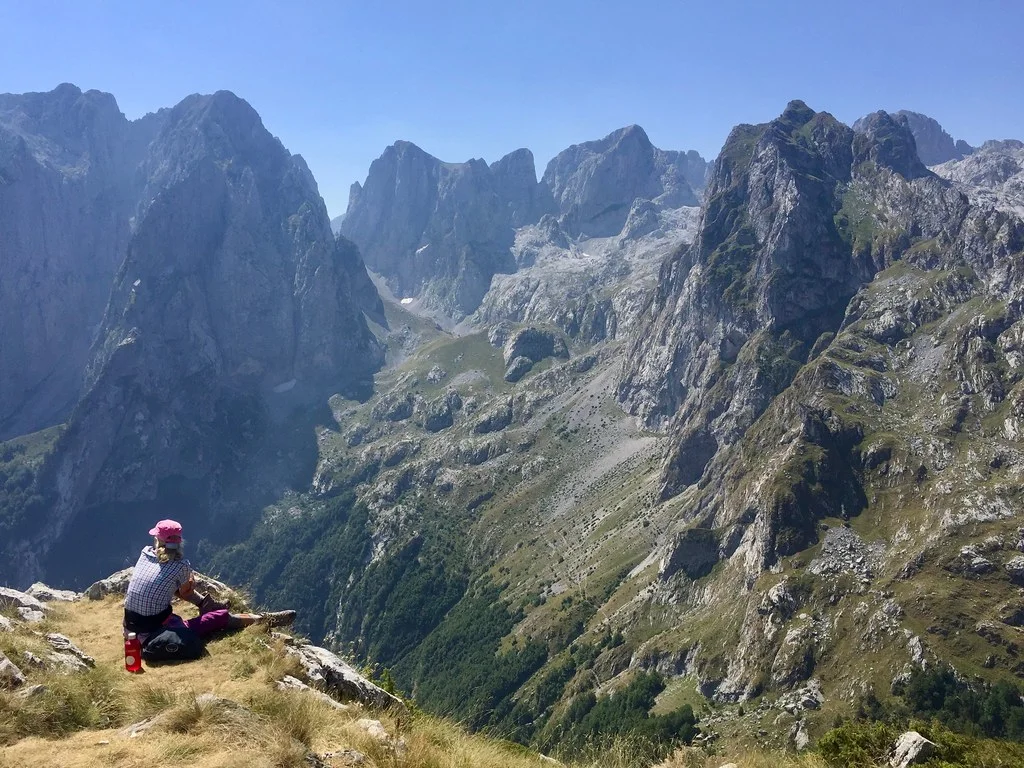 A hiker looks across the rugged limestone peaks of the Albanian Alps on the Peaks of the Balkans trail.