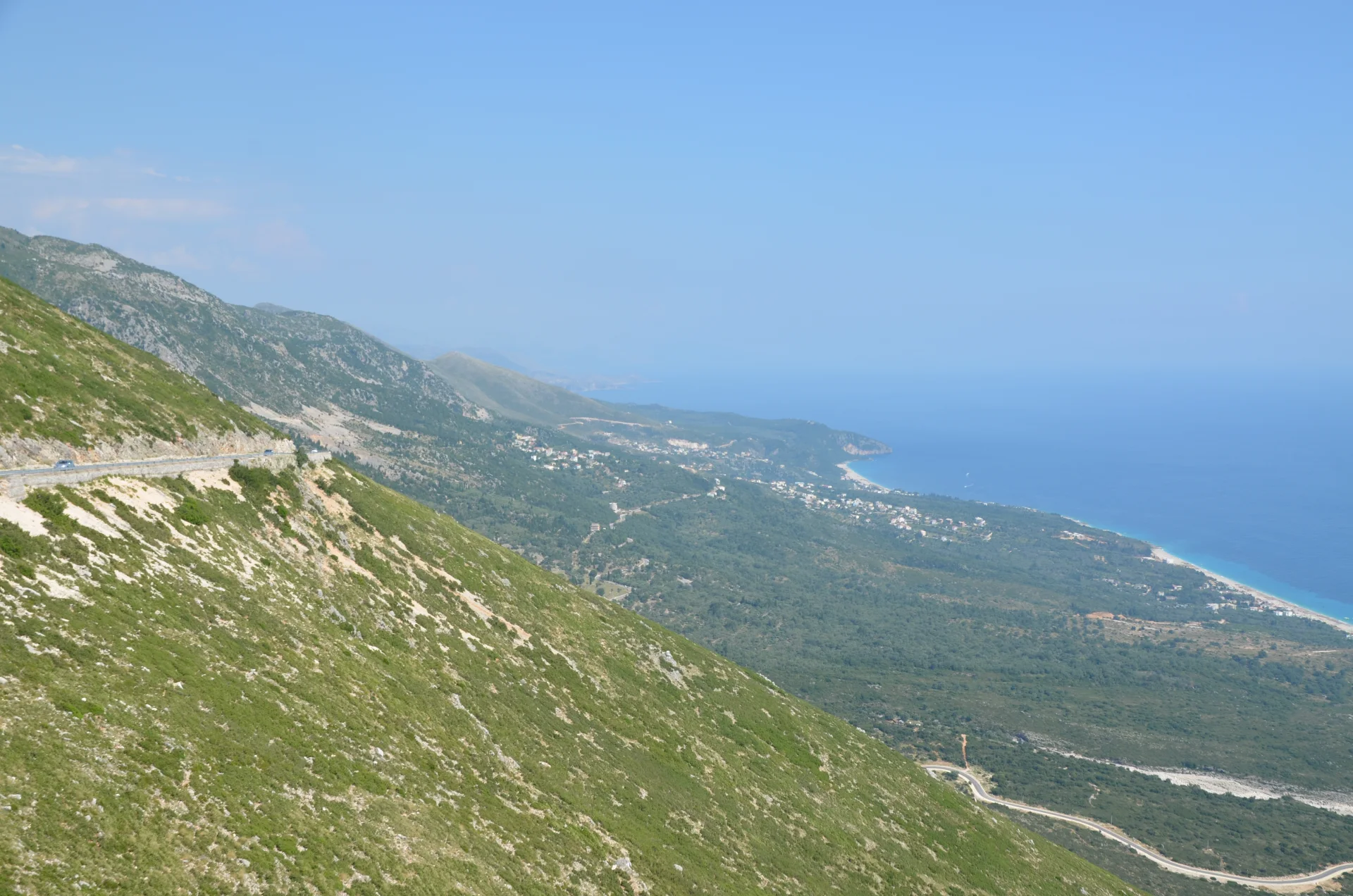 The Albanian Riviera's steep green slopes descending to the Ionian Sea near Dhërmi.