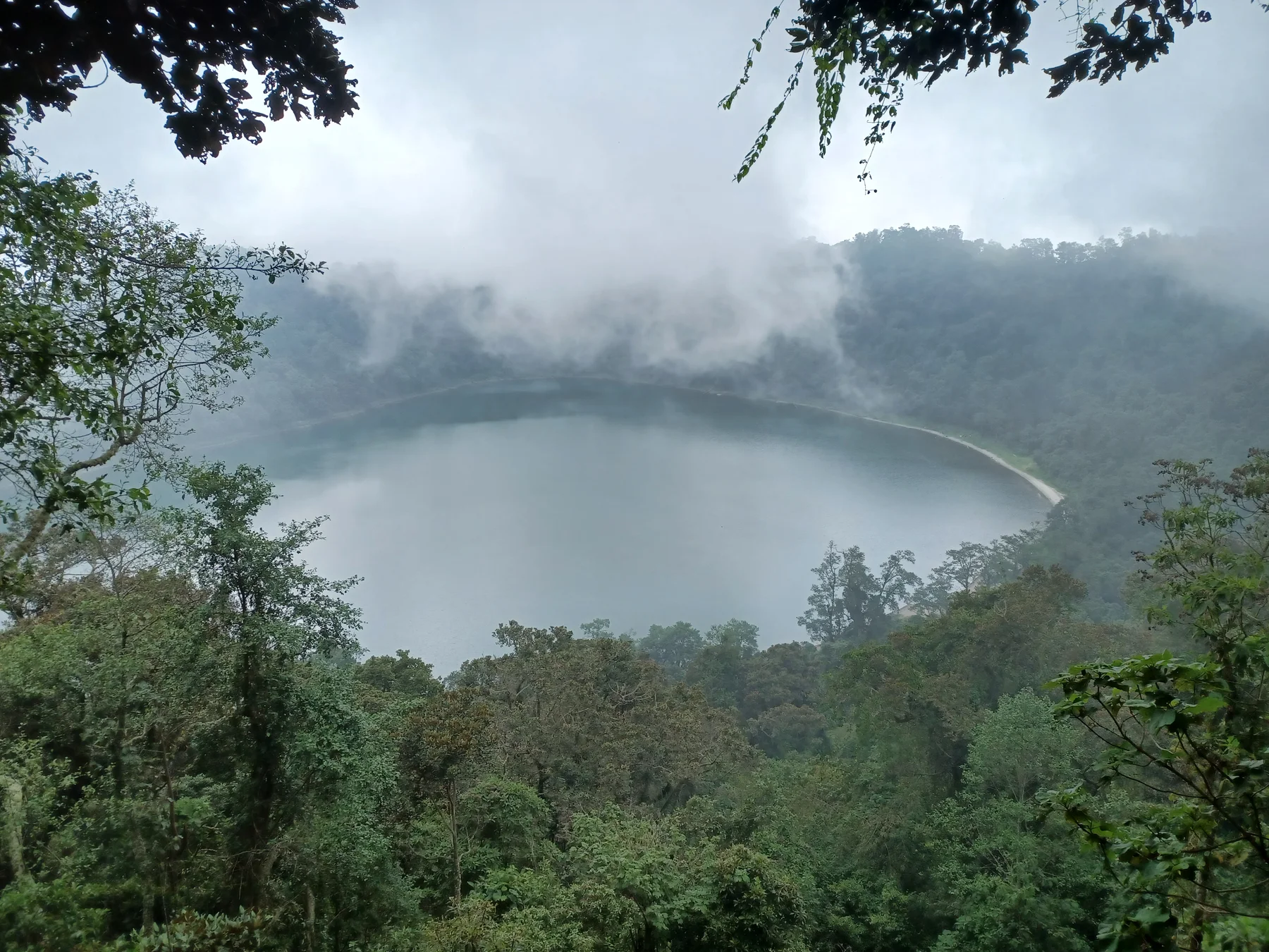 Mist drifting across the forested crater lake at Laguna Chicabal.