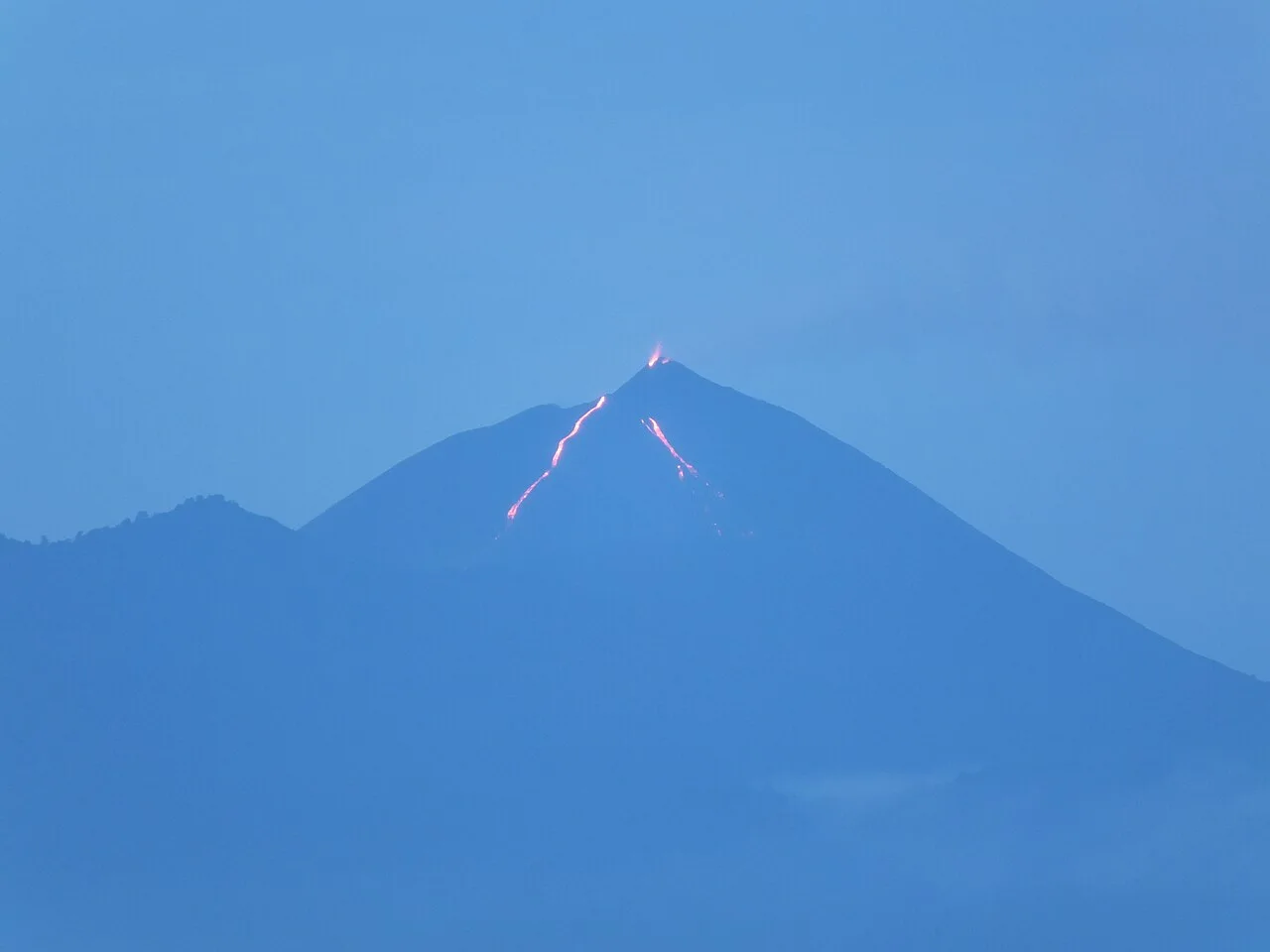 Glowing lava tracing down Pacaya's cone at dusk in Guatemala.