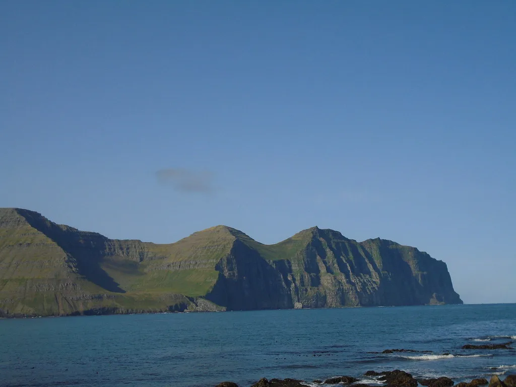 Steep green sea cliffs rising from the water in Hornstrandir.