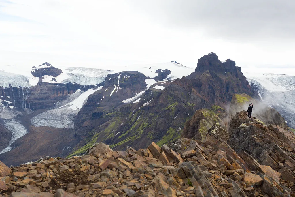 A hiker standing on the rocky Kristínartindar ridge above Skaftafell glaciers.