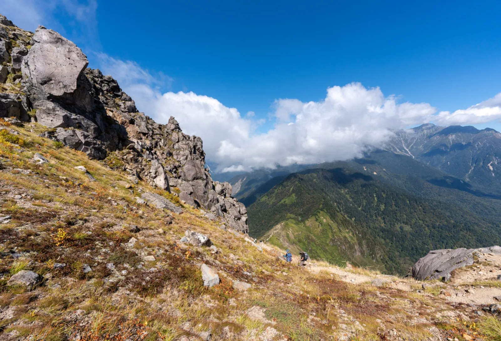 Hikers cross the rocky upper trail on Mount Yakedake.