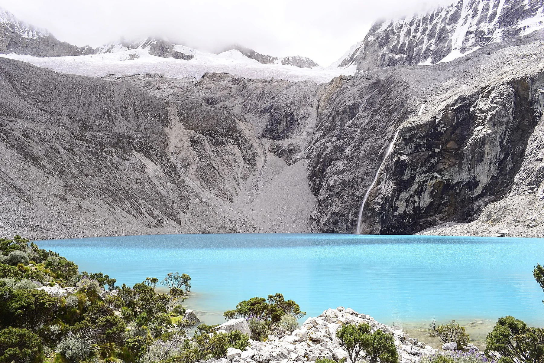 Turquoise Laguna 69 beneath glaciated peaks in Peru.