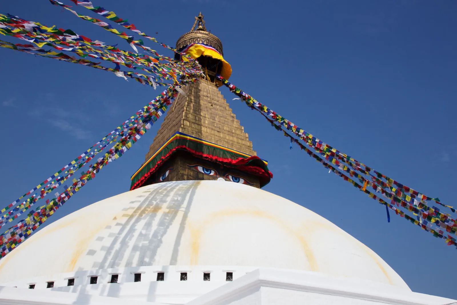 Boudhanath Stupa rises above the white dome and prayer flags.